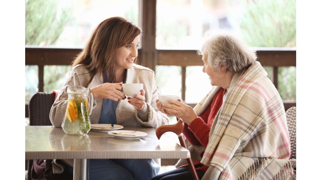 Old woman and caregiver having tea together