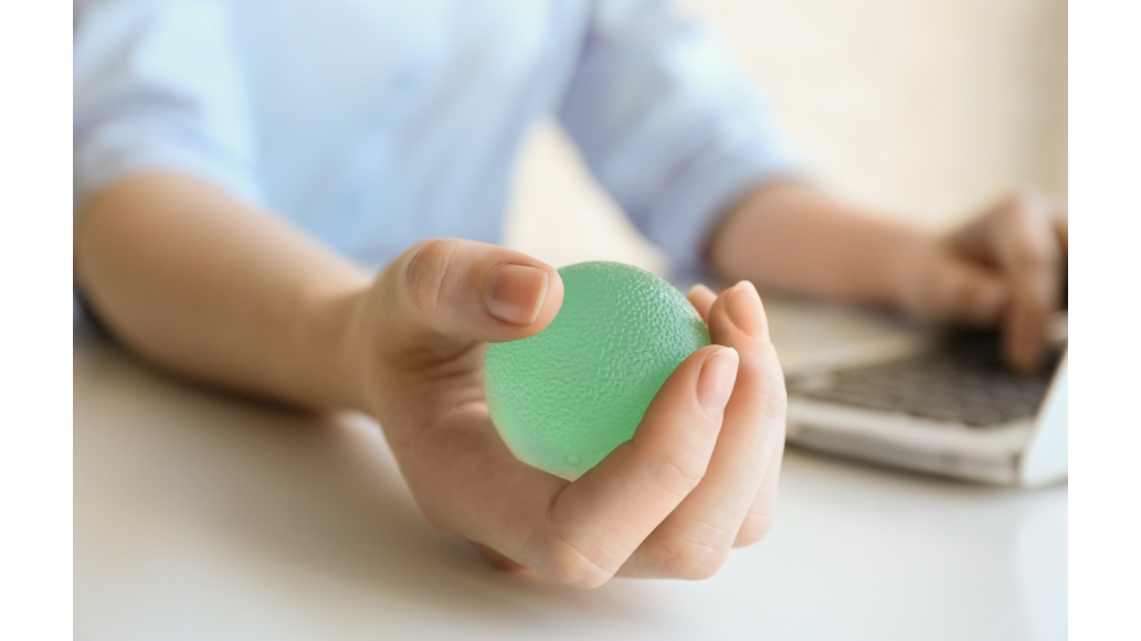 person with green hand exerciser ball