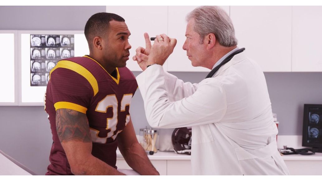 football player getting vision checked by doctor